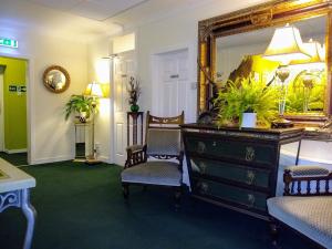 a room with a dresser and two chairs and a mirror at Rhins of Galloway in Cairnryan