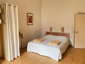een slaapkamer met een wit bed met 2 kussens erop bij Hotel het Oude Postkantoor in Brummen