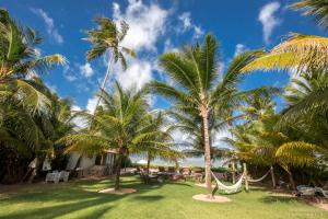 a resort with palm trees and a hammock at Pousada Casotas in Pôrto de Pedras