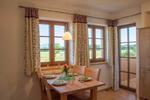 Heimhilgerhof في Seeon: غرفة طعام مع طاولة وكراسي ونوافذ