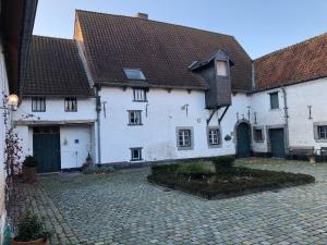 a white building with a black roof and a courtyard at B&B De Metstermolen in Sint-Truiden