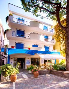 a large white building with blue balconies and plants at Hotel Adria B&B - Colazione fino alle 12 in Misano Adriatico