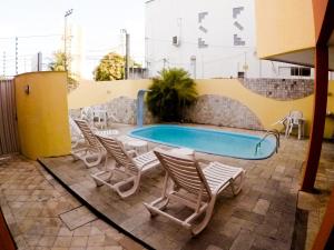 um grupo de cadeiras e uma piscina em Residencial Ponta Negra Flat em Natal