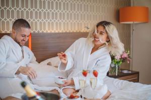 a man and a woman sitting on a bed at Hotel Angeleno in Los Angeles