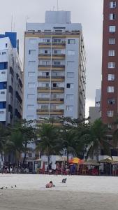 een persoon en een hond op een strand met een gebouw bij Apartamento mobiliado prédio frente ao mar in São Vicente