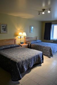 een hotelkamer met 2 bedden en een raam bij Motel Quatre Saisons in Forestville