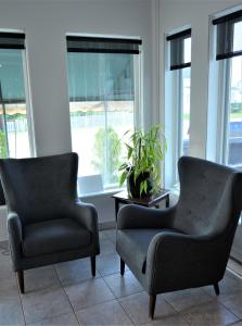 2 sillas y una mesa en una habitación con ventanas en Motel Quatre Saisons, en Forestville