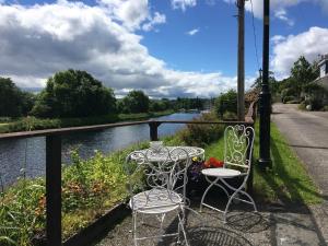 een tafel en stoelen op een balkon met een rivier bij Sealladh Sona in Inverness