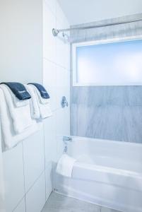 Baño blanco con bañera, ventana y toallas en Boutique Suite #2, en Blue Mountains