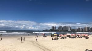 瓜魯雅的住宿－Guarujá Lindo - Pitangueiras，一群人在海滩上,带遮阳伞
