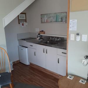
a kitchen with a sink, stove, and cabinets at Cottage Mews Motel in Taupo
