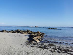 una playa con algunas rocas en el agua en Gîte bord de mer en Santec