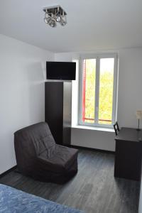 een woonkamer met een bank en een televisie bij Hotel Le Saint Julien in Saint-Julien-du-Sault