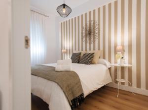1 dormitorio con 1 cama grande y paredes a rayas en Magno Apartments Azahares, en Sevilla