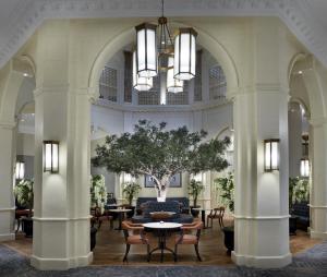 eine Lobby mit einem Tisch, Stühlen und einem Baum in der Unterkunft The Midland in Manchester