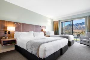 a hotel room with a large bed and a chair at Holiday Inn Queenstown Frankton Road, an IHG Hotel in Queenstown