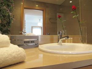 a bathroom sink with a vase of flowers and a mirror at Panoramic in Travel, Parque das Nações in Lisbon