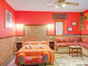1 dormitorio con paredes rojas, 1 cama y 1 sofá en Rural apartment with shared garden pool and Spa, en Galapagar