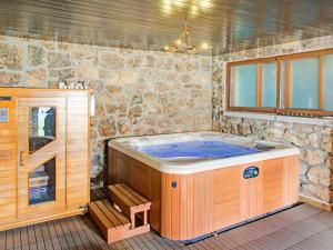 a jacuzzi tub in a room with a stone wall at Rural apartment with shared garden pool and Spa in Galapagar