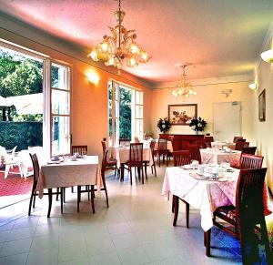 a restaurant with tables and chairs and a chandelier at Hotel Villa Fiorisella in Marina di Massa