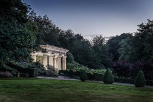 a garden with a building and trees and grass at Wotton House in Dorking