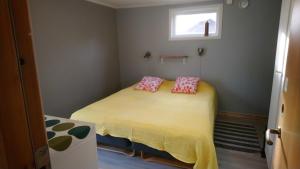 a small bedroom with a yellow bed with pink pillows at Björboholm in Gråbo