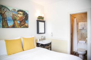 una camera da letto con un letto e un lavandino e un dipinto sul muro di Paia Inn a Paia