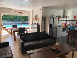 een keuken en een woonkamer met een bank en een tafel bij VILLA LA CHAUMIERE Au calme et sans vis à vis in Matoury