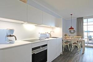 キュールングスボルンにあるHaus-Atlantik-Wohnung-3-16-98のキッチン(白いキャビネット、テーブル、椅子付)