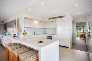 a kitchen with white cabinets and white appliances at Gemini Court Holiday Apartments in Gold Coast