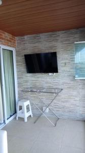 a wall with a tv and a stool in a room at Varandas do Francês in Maceió