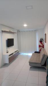 a living room with a couch and a flat screen tv at Varandas do Francês in Maceió