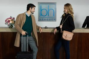 un hombre y una mujer de pie junto a un mostrador con una maleta en Hotel bh Usaquén, en Bogotá