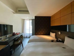 um quarto de hotel com duas camas e uma secretária em San Juan Easy Stay Inn Tainan em Tainan