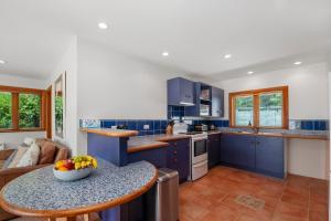una cocina con armarios azules y un bol de fruta en una mesa en Waters Edge Retreat - Motuoapa Holiday Home, en Turangi