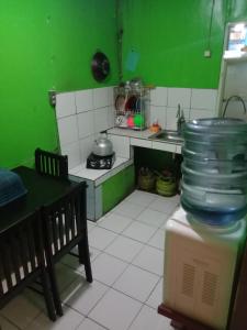 una cucina con pareti verdi, tavolo e bancone di Pondok orange ciwidey a Bandung