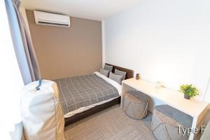 東京にあるHermitage Nishi Shinjuku のベッドとデスクが備わる小さな客室です。