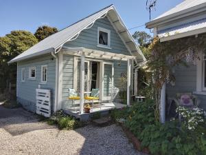 a small shed with a porch and a chair at 210 Hillsidecottage in Nelson