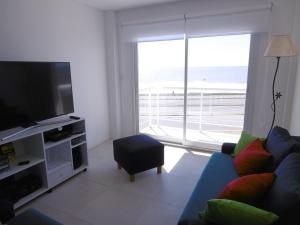 ein Wohnzimmer mit einem blauen Sofa und einem TV in der Unterkunft DEPTOS VIP en EDIFICIO FRENTE AL MAR-ZONA CONSTITUCION in Mar del Plata