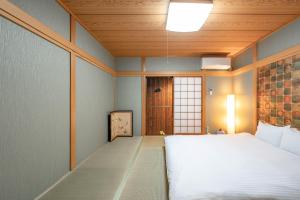 a bedroom with a white bed and a wooden ceiling at Kamo River J~House in Kyoto