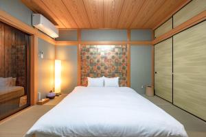 a bedroom with a large white bed and wooden ceilings at Kamo River J~House in Kyoto