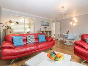 a living room with a red couch and a table at Fowey Cottage in Coffinswell