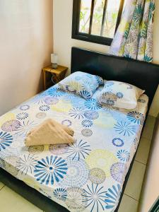 a bed with a blue and white comforter and pillows at Le MélanZé in Grande Anse