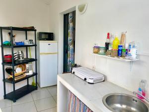 a kitchen with a sink and a white refrigerator at Le MélanZé in Grande Anse