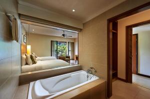 a bathroom with a tub and a bed in the mirror at The Taaras Beach & Spa Resort in Redang Island