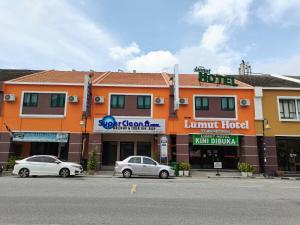 two cars parked in front of a building at Lumut Hotel in Lumut
