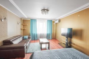 ein Wohnzimmer mit einem Sofa und einem Flachbild-TV in der Unterkunft Apartments Abazhur on Kareltseva 101 in Kurgan