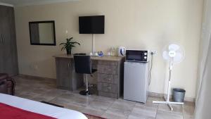 a bedroom with a desk with a refrigerator and a fan at Carnival View Guest Lodge and spa in Boksburg