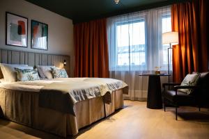 a bedroom with a bed and a chair and a window at Quality Hotel Prinsen in Trondheim