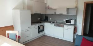 eine Küche mit weißen Schränken und einer Mikrowelle in der Unterkunft Ferienwohnung Thanner in Stumm